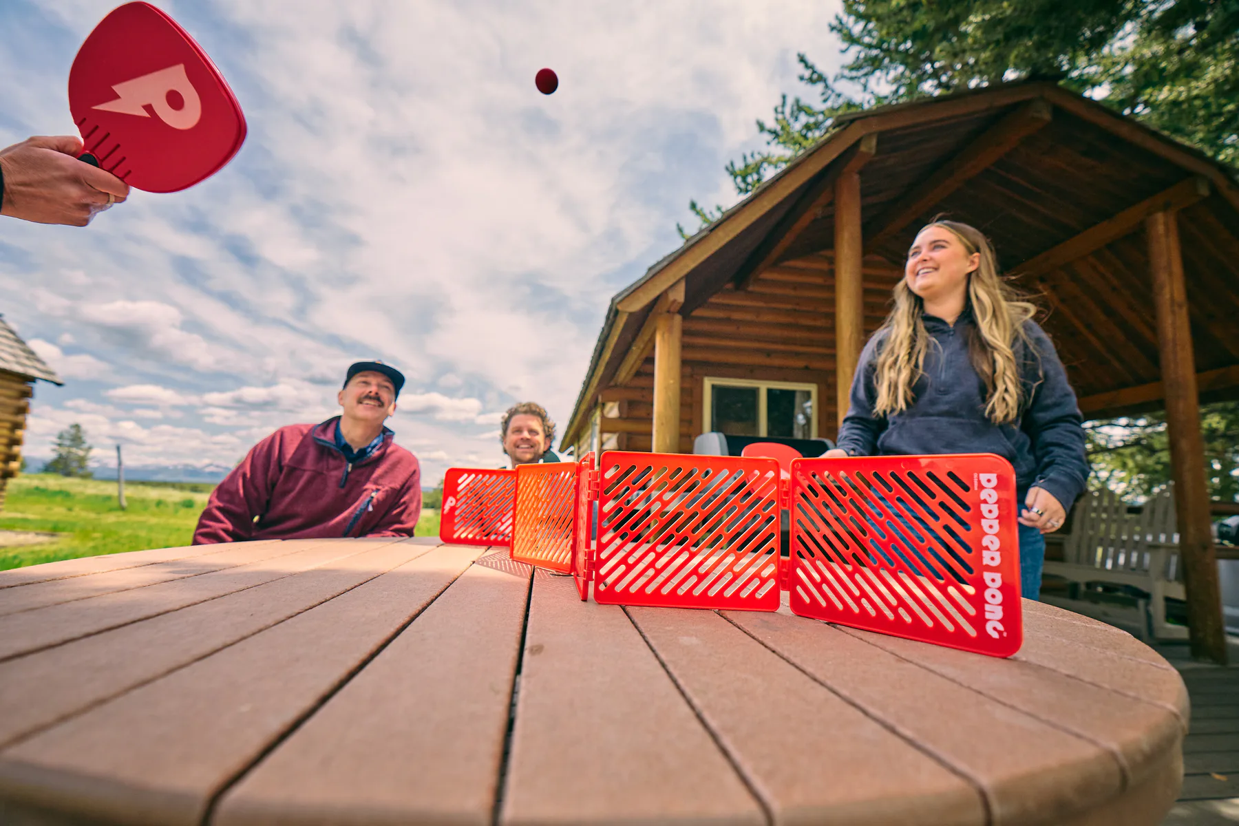 Friends playing Pepper Pong outdoors around a table